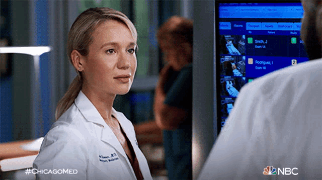 a woman in a lab coat stands in front of a monitor with the nbc logo visible