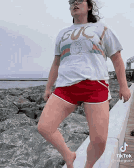 a woman in a gucci shirt and red shorts