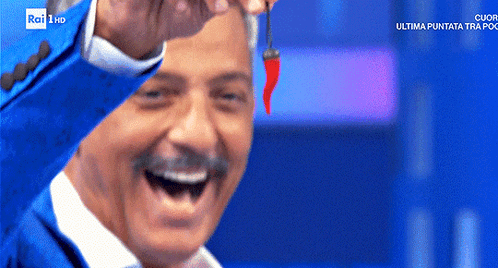 a man in a blue suit is holding a red pepper in front of a rai 1 hd screen
