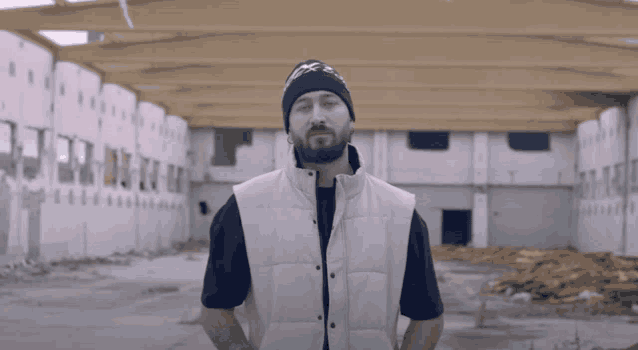 a man with a beard wearing a beanie and a vest