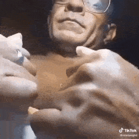 a man wearing glasses is holding a piece of paper in his hand .