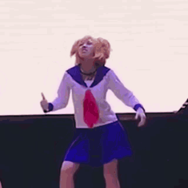 a woman in a sailor suit and blue skirt is dancing on a stage .
