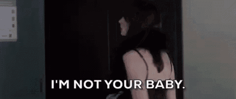 a woman in a black dress is standing in a dark room and says `` i 'm not your baby '' .