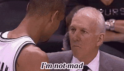a man in a suit and tie is talking to a basketball player in a basketball uniform .
