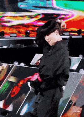 a man in a black jacket is dancing on stage