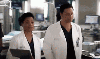 a man and a woman are walking in a hospital room .