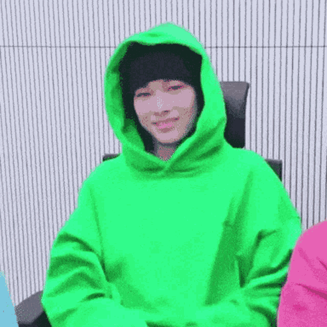 a person wearing a green hoodie and a black hat is smiling .