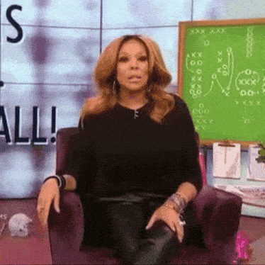 a woman is sitting in a chair in front of a green board with the word all on it