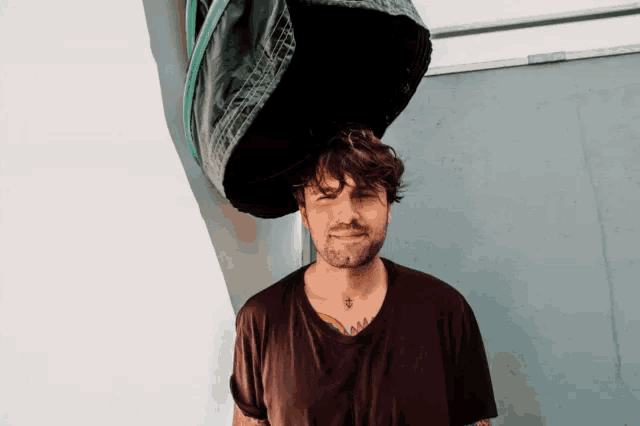 a man wearing a black shirt has a large black bag on his head