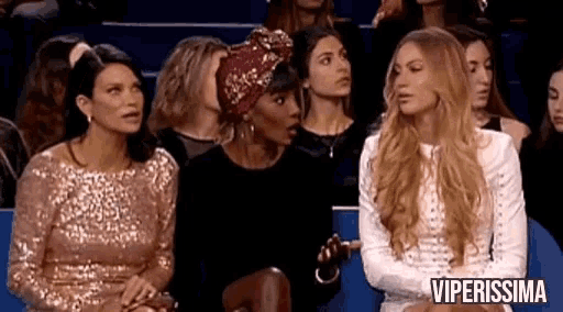 a group of women are sitting in a row and one of them is wearing a head scarf .