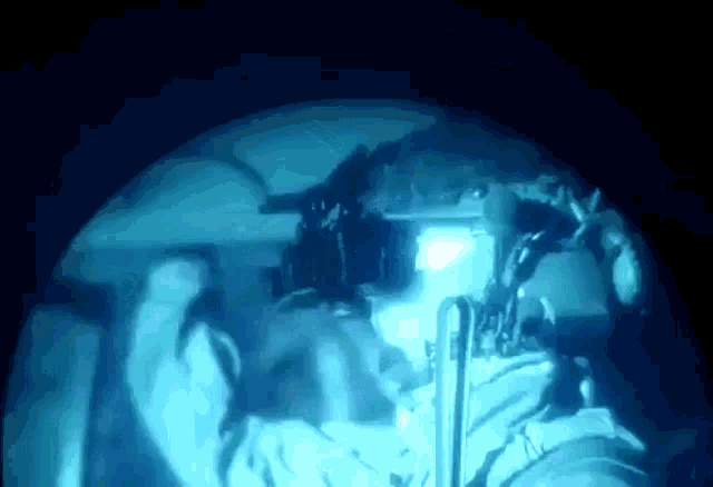 a man in a helmet is looking through a binoculars in the dark