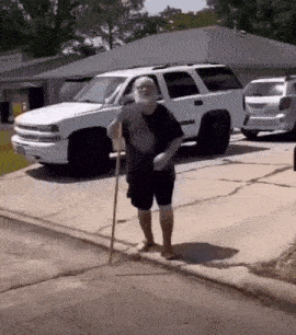 a man with a cane is walking down the sidewalk in front of a white suv .