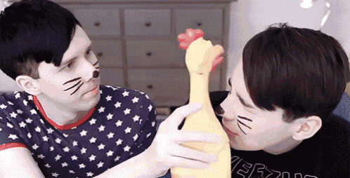 two men with cat faces on their faces are holding a chicken toy .