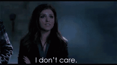 a woman is standing in the dark with her arms crossed and says i don 't care .