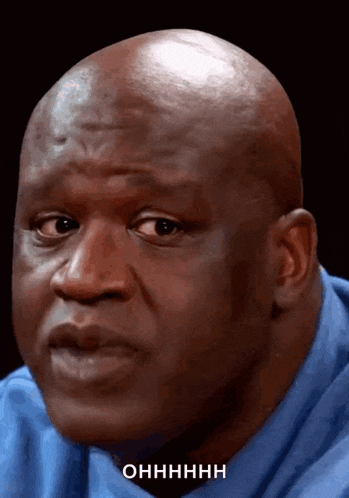 a bald man in a blue shirt says ohhhhh on his face