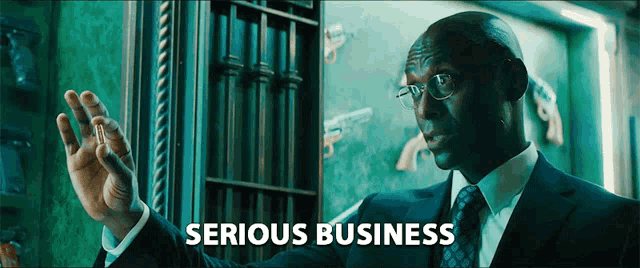 a man in a suit and tie says serious business in front of a safe