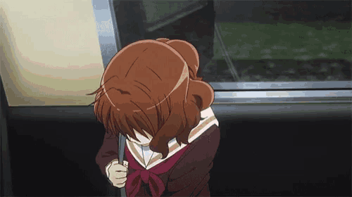 a girl in a school uniform is sitting on a train looking out the window