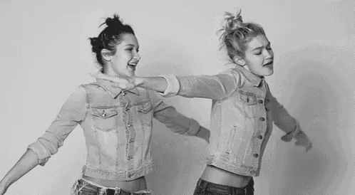 a black and white photo of two women wearing denim jackets and dancing .