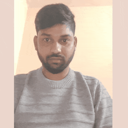 a man with a beard is wearing a gray sweater