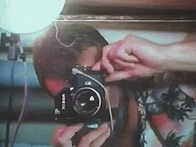 a person is taking a picture of themselves in a mirror with a nikon camera .
