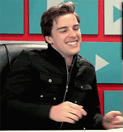 a young man wearing a black jacket is smiling