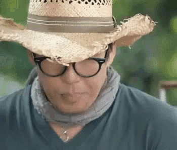 a man wearing a straw hat and glasses .