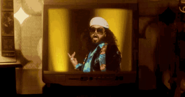 a man with a beard and sunglasses is being projected on a television screen