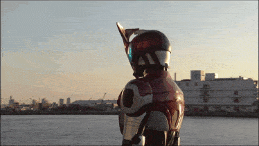 a person in a red and silver costume stands in front of a body of water