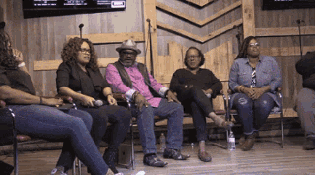 a group of people sitting in chairs with microphones in front of them