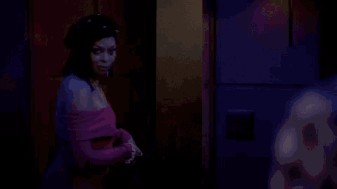 a woman in a pink off the shoulder dress is standing in a dark room .