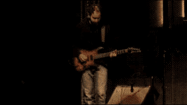 a man in a black shirt is playing a guitar
