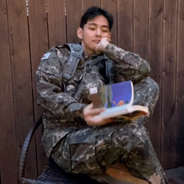 a man in a camouflage uniform is reading a book