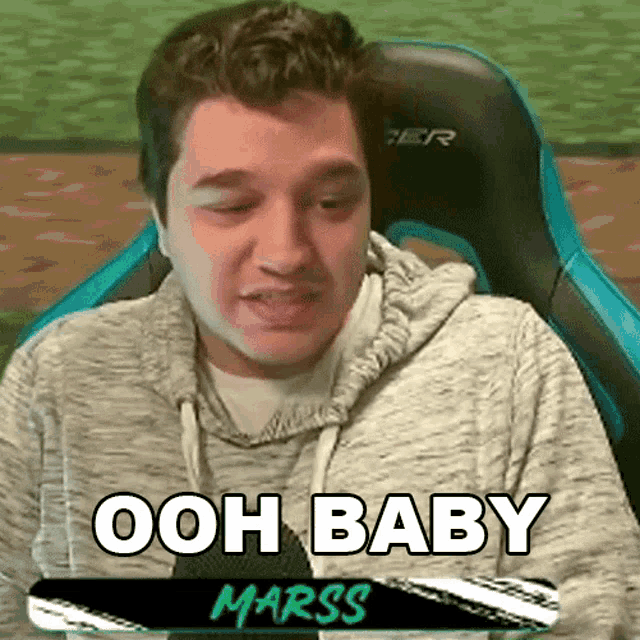 a man is sitting in a chair with the words `` ooh baby marss '' written on the screen .