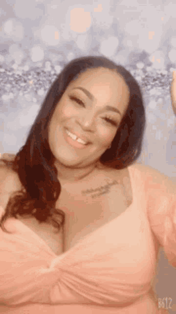 a woman in a pink top with a tattoo on her chest is smiling .