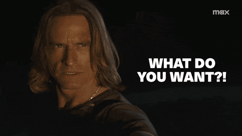 a man with long hair is looking at the camera with the words what do you want below him