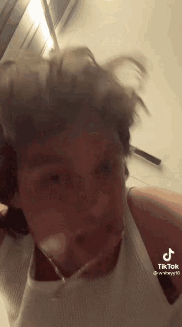 a man wearing headphones and a white tank top is making a funny face in a tik tok video .