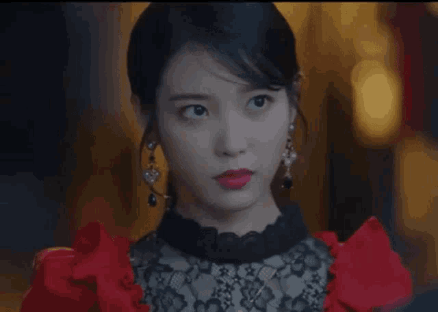 a woman wearing a red dress and black lace top is making a funny face .