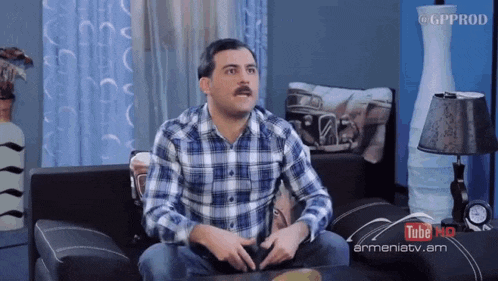 a man in a plaid shirt is sitting on a couch in front of a youtube ad