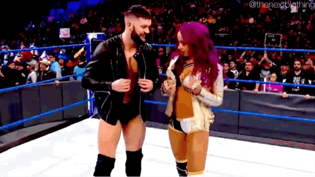 a man and a woman are standing in a wrestling ring with purple hair .
