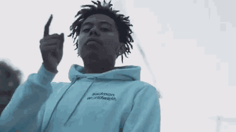 a young man wearing a white hoodie is giving the middle finger .