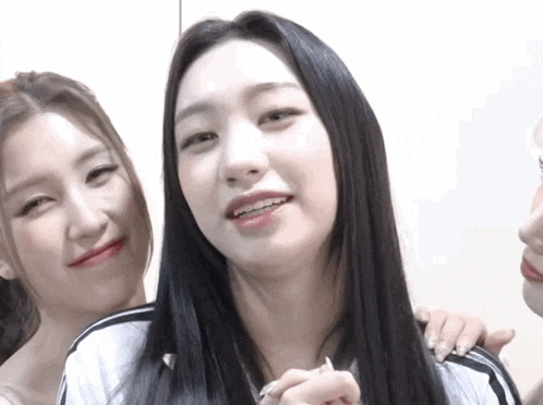 a woman with long black hair looks at the camera while another woman looks on
