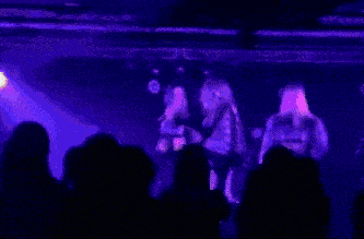 a group of people are standing in a dark room with purple lights