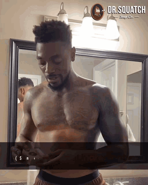 a shirtless man stands in front of a mirror with dr.squatch soap co. written on the bottom