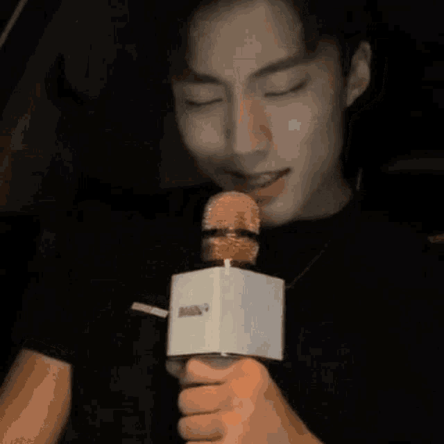 a young man is singing into a microphone while sitting in a car .