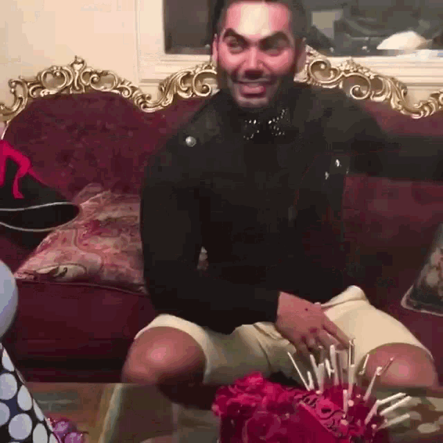 a man is sitting on a couch with a birthday cake on the table
