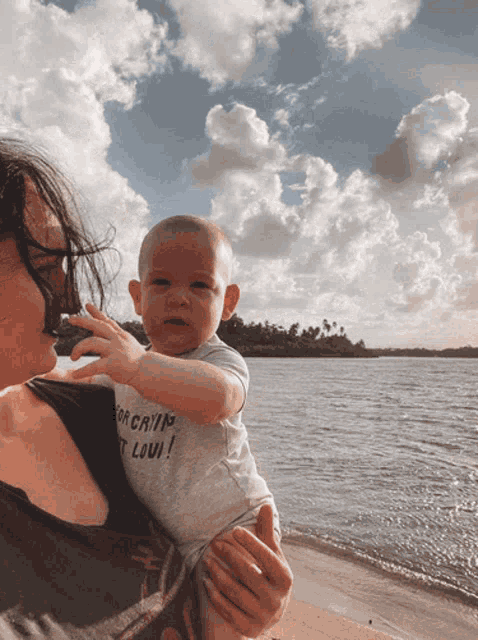 a woman is holding a baby who is wearing a shirt that says for crying out loui