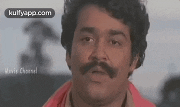 a man with a mustache is making a funny face and looking at the camera .