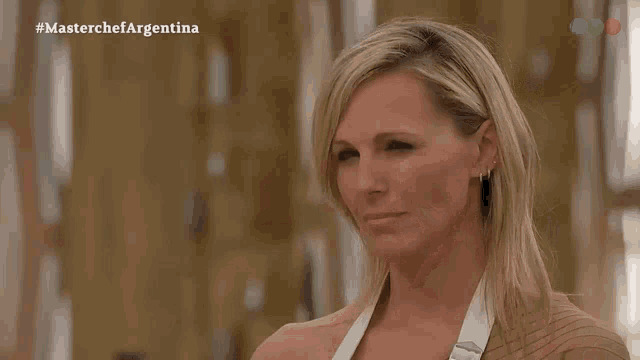 a blonde woman is smiling in front of a screen that says masterchef argentina