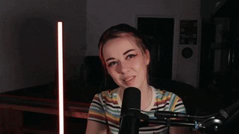 a woman is smiling in front of a microphone with the words cuppa deez nutz written above her