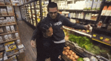 a man wearing a sweatshirt that says ' supreme ' on it is helping another man in a grocery store